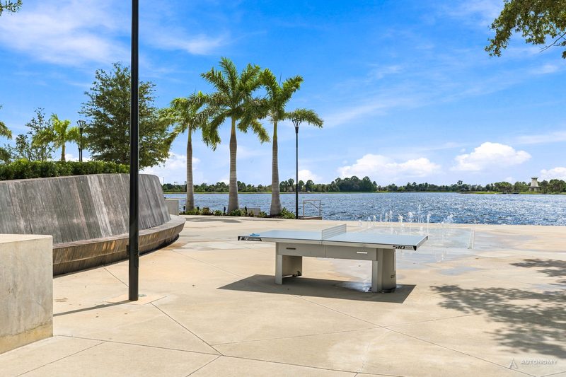 Outdoor table-tennis table on the Downtown Wellen lakefront plaza with royal palms and the Grand Lake